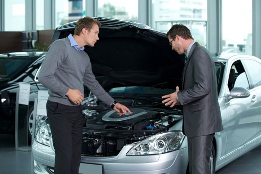 Car salesperson explaining about car's engine to customer