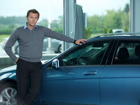 Portrait of young man standing by new car

