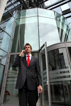 young caucasian businessman at office revolving door with cellphone