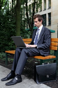 young caucasian businessman using his laptop in park