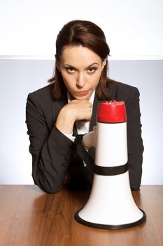 Portrait of businesswoman with megaphone kept of desk
