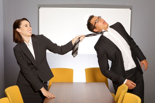 Businesswoman pulling businessman by tie