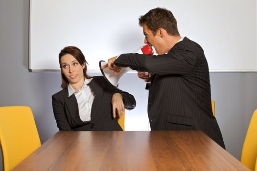 Businessman shouting at businesswoman through megaphone