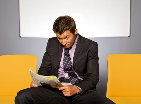 Businessman making face while reading newspaper