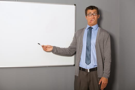 Portrait of businessman pointing at whiteboard and making face in office