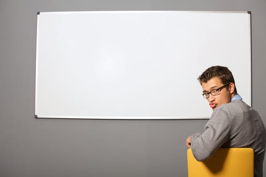 Portrait of businessman making face in front of whiteboard in office