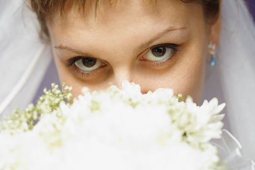 The eyes of the bride and bridal bouquet closeup