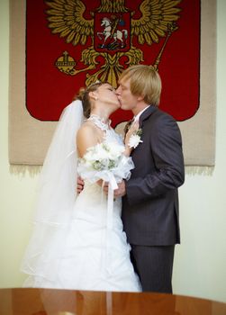 Newly married kiss at wedding ceremony under Russian arms
