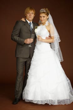 Smart studio portrait of the groom and the bride with wine glasses