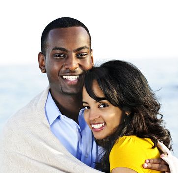 Young romantic sharing a blanket by the ocean