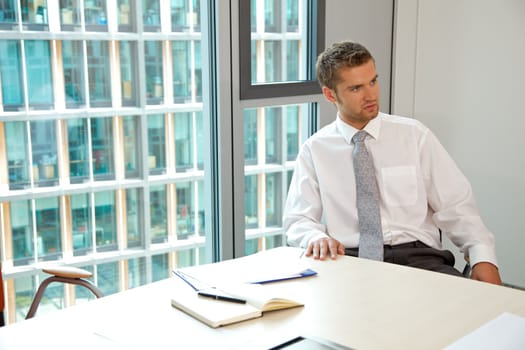 Young confident caucasian businessman sitting at the office desk