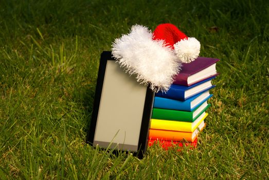Electronic book reader wearing Santa's hat with stack of books