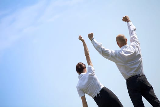 Rear view of business couple with arms outstretched standing in park