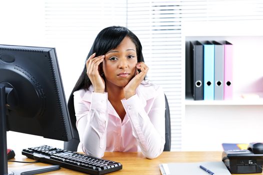 Unhappy young black business woman at desk in office