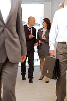 Business team walking thru corridor and talking