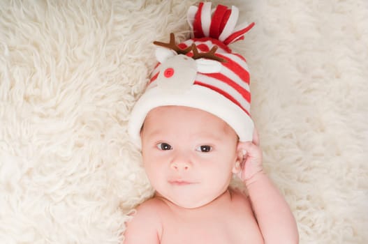 Newborn baby in chritstmas hat lies on fur