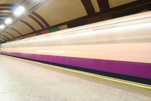 London subway station with train speeding past
