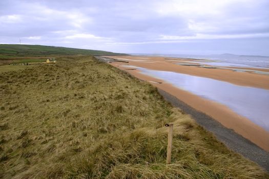 a view of the coastal dunes and an old cottage and windmill on the west coast of ireland