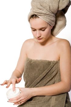 Young woman in towel on a white background taking care of herself