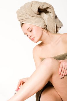 Young woman in towel on a white background grooming herself