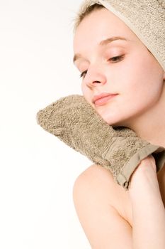 Young woman in towel on a white background cleaning herself