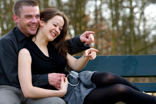 Man and girlfriend on a bench in a park having fun