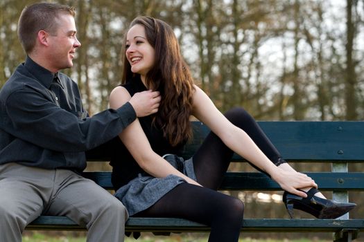 Man and girlfriend on a bench in a park having fun