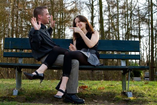 Man and girlfriend on a bench in a park having fun