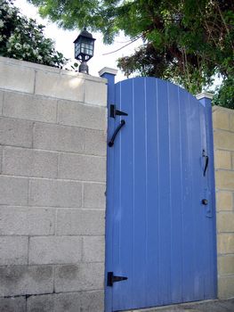 a blue gate set into a grey brick wall.