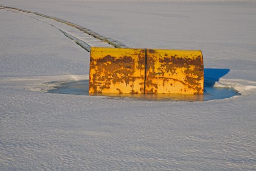 Yellow barrel in the frozen lake