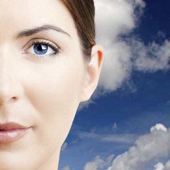 Close-up portrait of a beautiful young woman with  a cloudy sky on the background