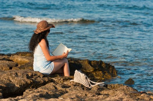 Woman ejoying a book with her feet in the water