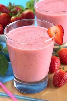Fresh strawberry milkshake (Selective Focus, Focus on the strawberry slice on the rim of the glass)
