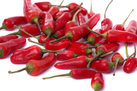 Detail view of a bunch of red chili peppers scattered isolated on a white background.