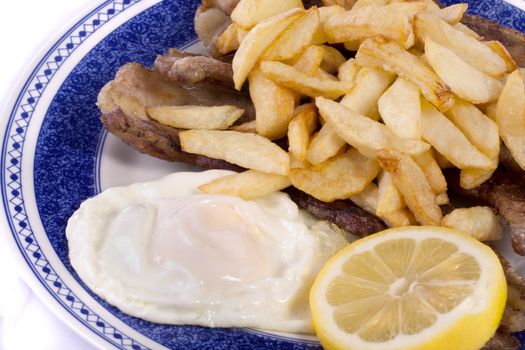 Close up view of a bunch of fried potatoes in slices, with egg and roasted meat. 