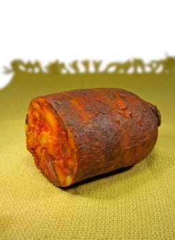 Red chorizo on top of a yellow cloth, on a white background, sliced in half.