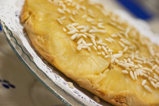 Close view of a homemade pineapple cake decorated with pine nuts.
