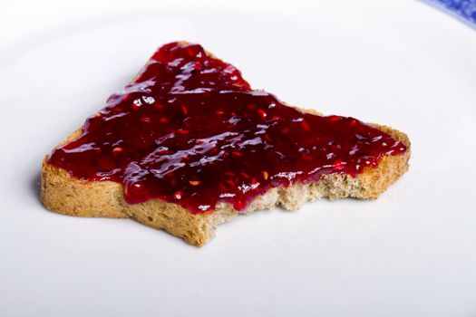 Close view of a toasted bread with berry jam spread  isolated on a white background.