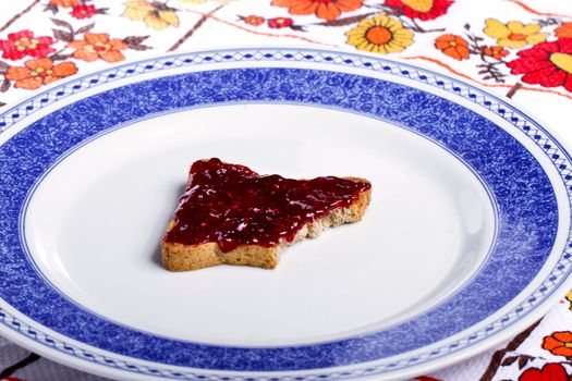 Close view of a toasted bread with berry jam spread  isolated on a white background.