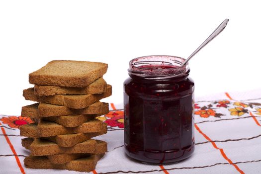 Close view of a toasted bread with berry jam jar isolated on a white background.