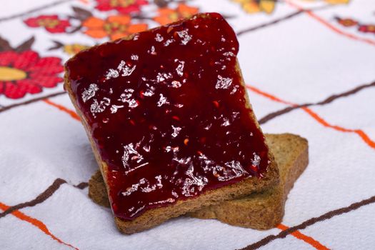 Close view of a toasted bread with berry jam isolated on a white background.