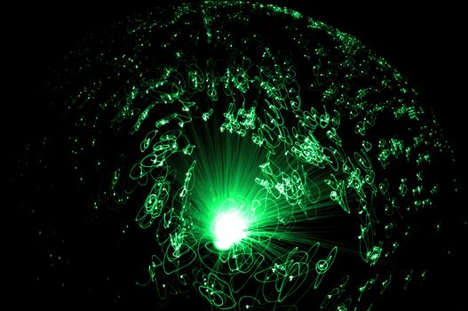 Catching the movement of the ends of many illuminated green fiber optic strands against a black background.