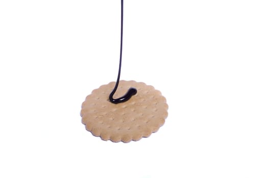 View of a round biscuit isolated on a white background with a drip of dark chocolate.