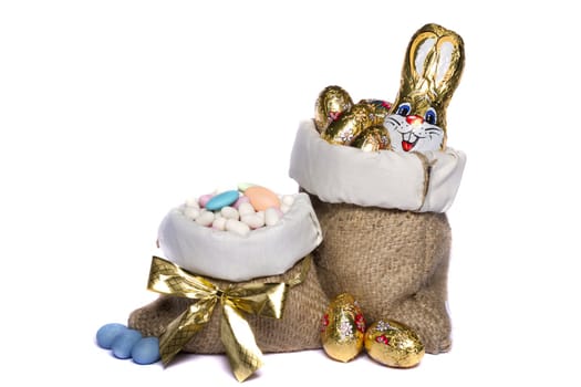Close up view of sweet almonds and chocolate eggs inside a sack isolated on a white background.