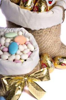 Close up view of sweet almonds and chocolate eggs inside a sack isolated on a white background.