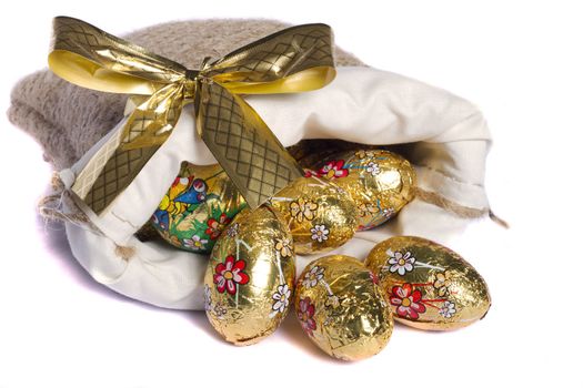 Close up view of sweet golden eggs inside a sack isolated on a white background.
