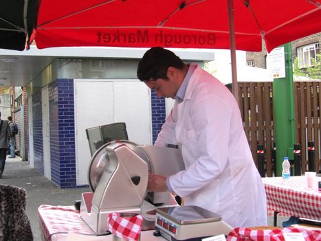 LONDON - AUGUST 14: Unidentified man at ham stall at Borough Market on August 14, 2010 in London. Borough Market is one of the largest gourmet food markets in London.                          