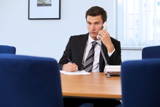 Portrait of businessman conversing on landline phone