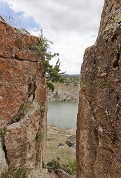 portrait looking through a gorge of a tarn lake in Cappadocia, Turkey, clouds, blue sky, crop space, copy space and vertical