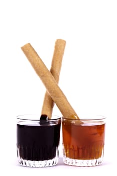 Close up view of a glass of honey and another of chocolate with cookie rolls.